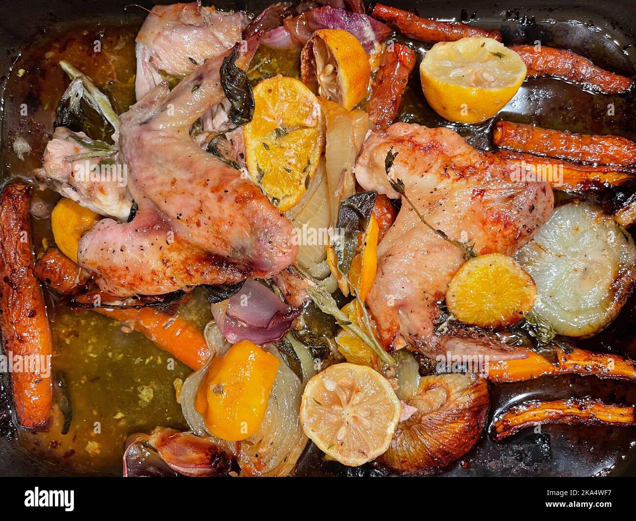 Ansicht von oben auf geröstete Hähnchenflügel, Karotten, Zwiebeln, Orange, Thymian und Salbei, um eine Soße zu machen Stockfoto