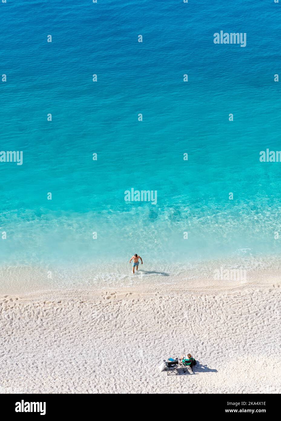 Ein wunderschöner Sandstrand mit kristallklarem Wasser und einem Paar, das seinen Urlaub genießt. Stockfoto