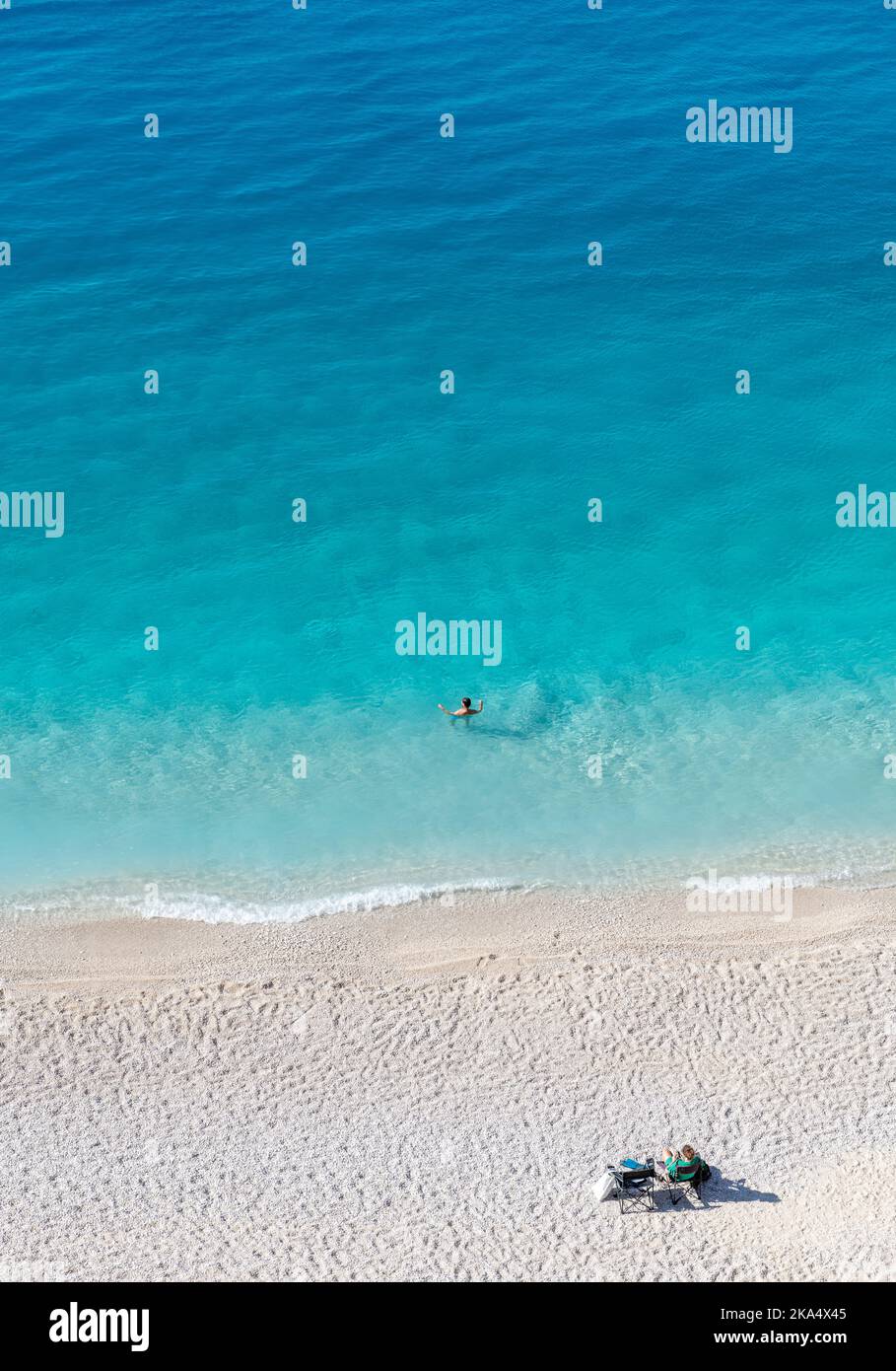 Ein wunderschöner Sandstrand mit kristallklarem Wasser und einem Paar, das seinen Urlaub genießt. Stockfoto