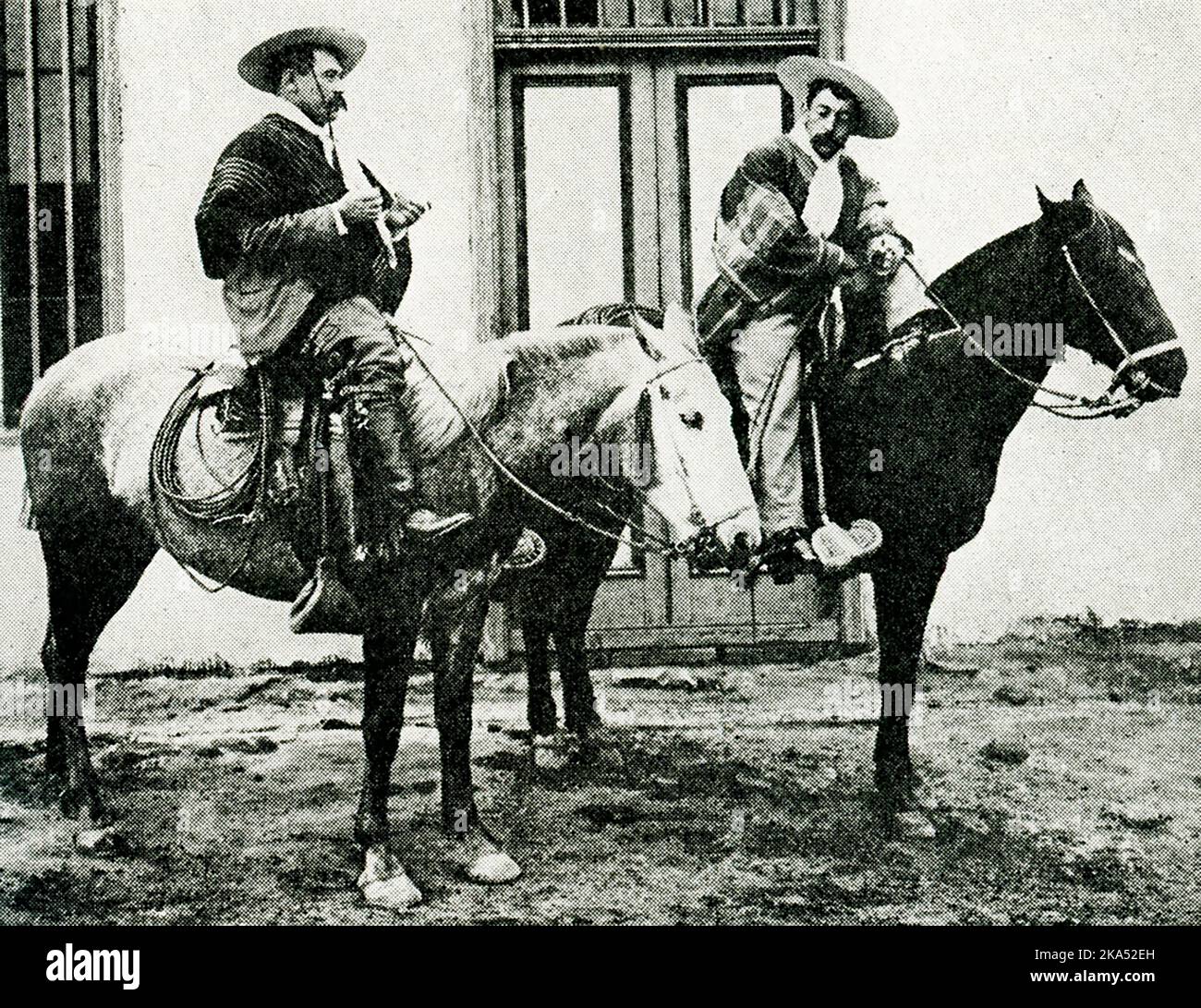 Diese Abbildung aus dem Jahr 1914 zeigt zwei Reiter (oder Cowboys) in Chile. Der Bildunterschrift zufolge wird ein chilenischer Cowboy oder Reiter nie ohne seinen breiten Rundkrempelhut, seinen bunten Umhang und seinen Bandschlitz um die Taille gesehen. Sie sind als Guasos oder huasos bekannt. Stockfoto