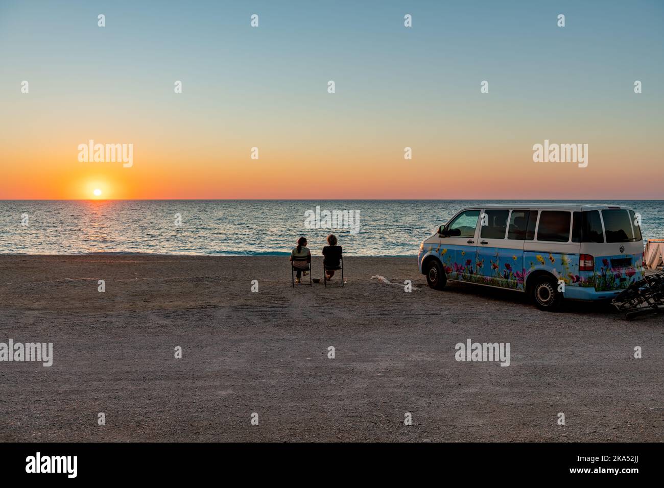 Insel Lefkada. Griechenland-10.17.2022. Ein Wohnmobil parkte an einem Strand mit einem Paar, das ein Glas Wein und den Sonnenuntergang genoss. Stockfoto