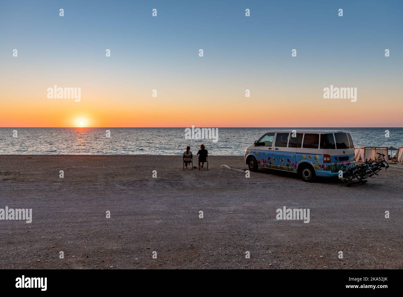 Insel Lefkada. Griechenland-10.17.2022. Ein Wohnmobil parkte an einem Strand mit einem Paar, das ein Glas Wein und den Sonnenuntergang genoss. Stockfoto