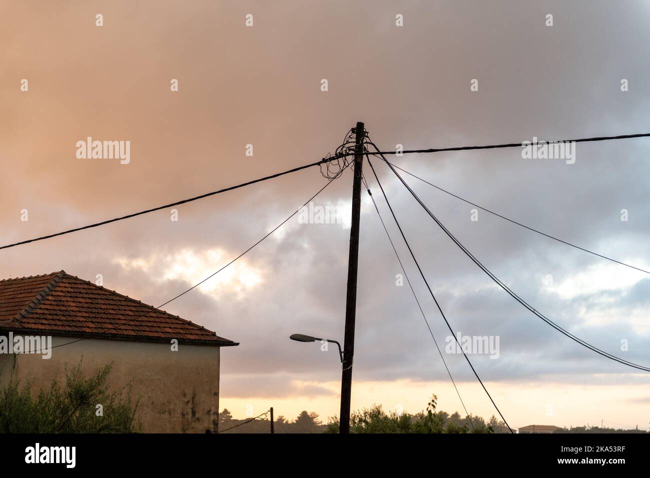 Eine Stromleitung auf einem Holzpfahl über dem Kopf, die Strom zu einem Haus in einem ländlichen Gebiet liefert. Stockfoto