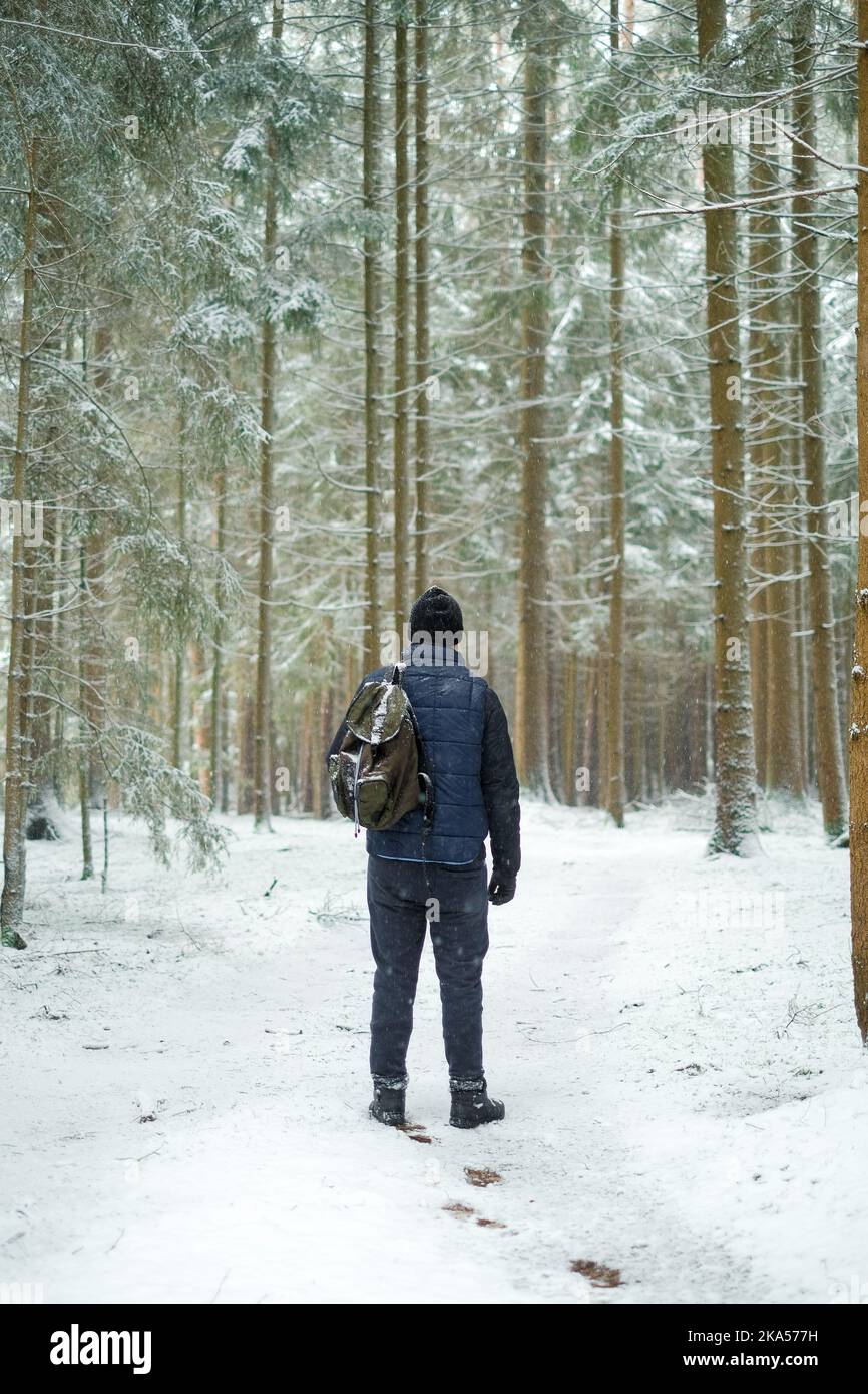 Der Mensch in der kalten Jahreszeit in der natürlichen Umgebung. Reisende im Winter verschneiten Wald.Mann mit einem Rucksack bei verschneiten Wetter. Winterwetter. Stockfoto