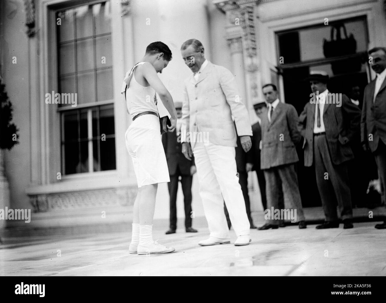 STAFFELLAUF STARTET AM WEISSEN HAUS. Fred Reed schüttelt sich die Hände mit Präsident Woodrow Wilson beim Start eines Scout-Staffellaufs, das im Weißen Haus begann, aufgenommen 1913. Stockfoto