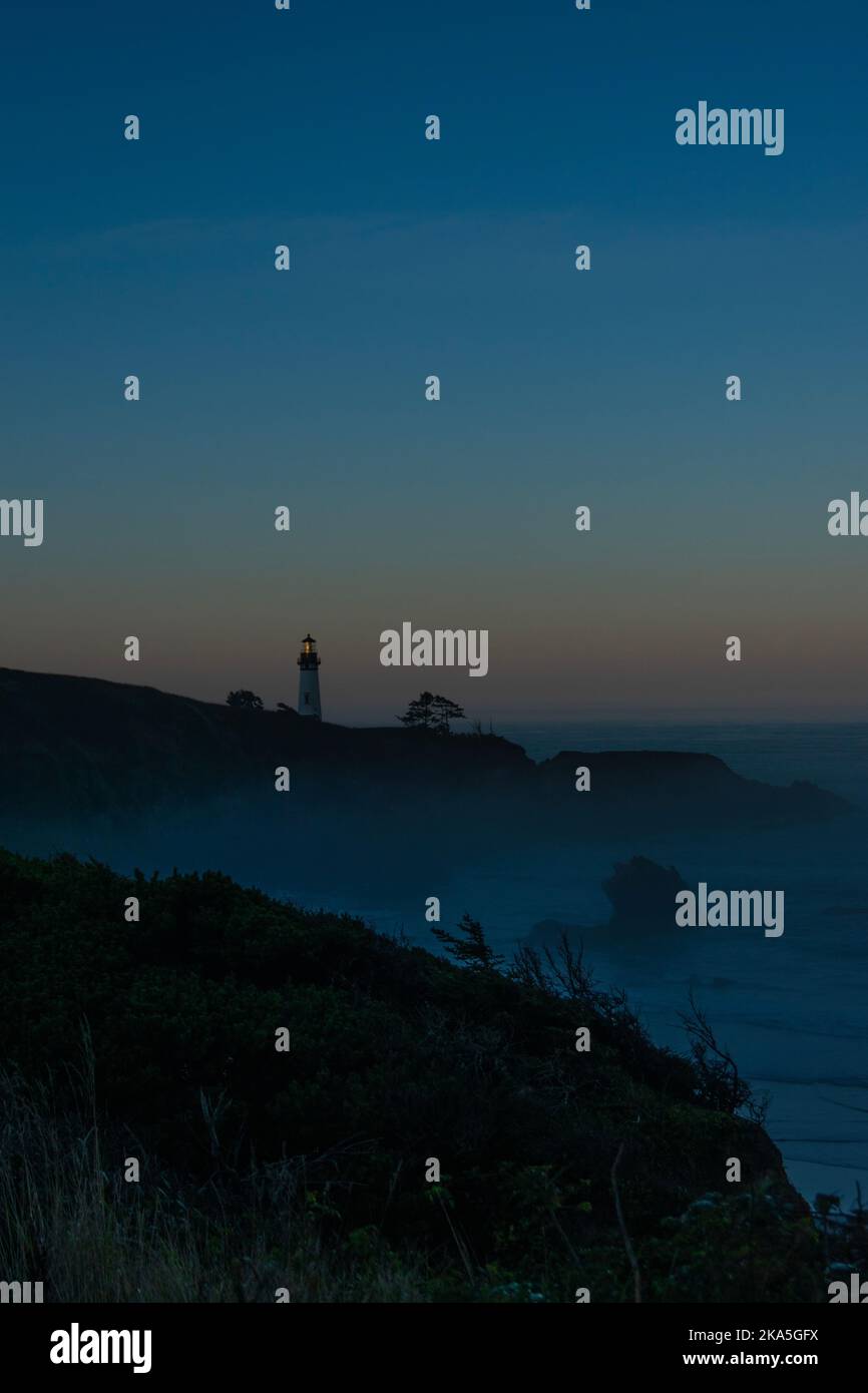 Sonnenaufgang am Yaquina Head Lighthouse in Newport, Oregon. Der Leuchtturm liegt an einem felsigen Ausstreichen, darunter das Meer mit einer Nebelschicht auf der Be Stockfoto