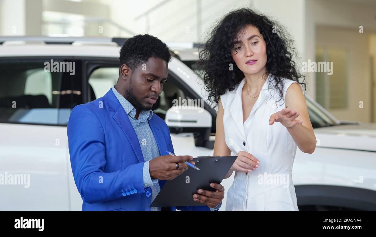 Afroamerikanischer Verkäufer präsentiert dem Kunden das Auto Stockfoto