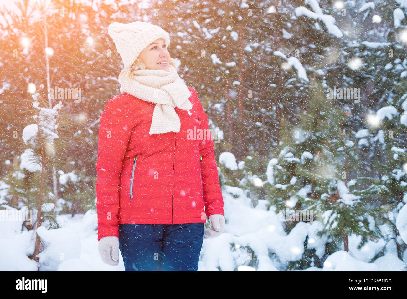 Frau spielt mit Schnee und läuft im Wald über Schneefall Stockfoto