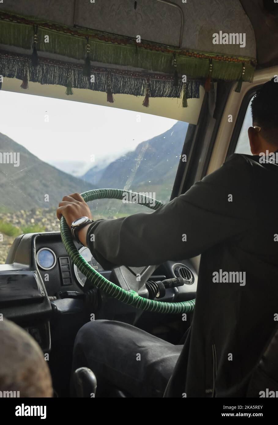 Rückansicht eines unbekannten Mannes, der während der Sommersaison auf der Manali-Leh-Autobahn einen Kleinbus fährt Stockfoto