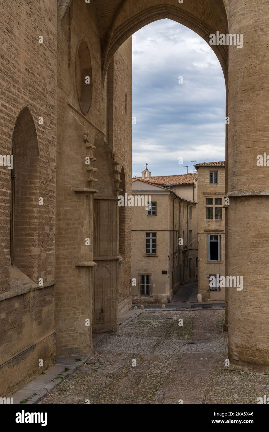 Malerischer Blick auf die alte Kopfsteinpflasterstraße und alte Gebäude, eingerahmt vom Eingangsportal der St. Peter Kathedrale im historischen Zentrum von Montpellier, Frankreich Stockfoto