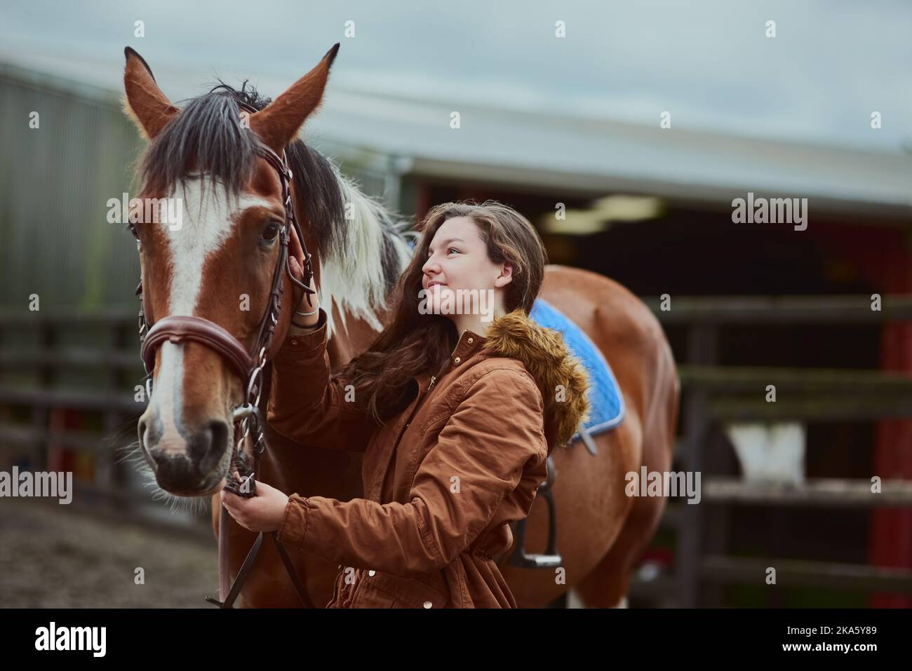 Halten Sie Ihre Freunde in der Nähe. Ein Teenager-Mädchen neben ihrem Pony auf einem Bauernhof stehen. Stockfoto