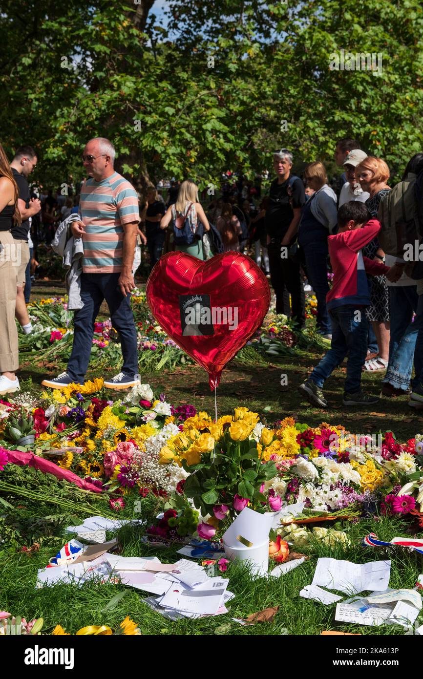 Ein roter, herzförmiger Ballon schwebt über einer floralen Hommage im Green Park, die von Trauernden zum Gedenken an den Tod von Königin Elizabeth II. Hinterlassen wurde. Green Park, London, U Stockfoto