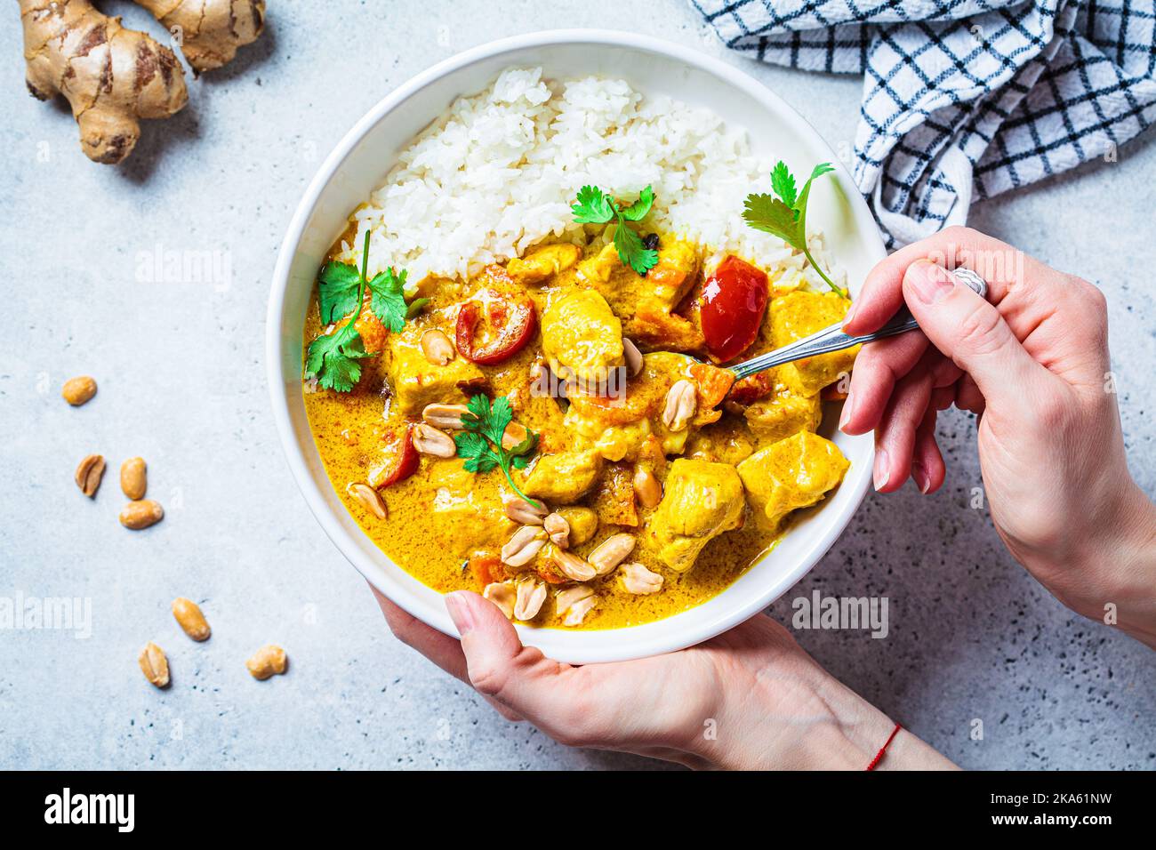 Thailändisches Hühnchen- und Erdnusscure mit Reis in einer weißen Schüssel, grauer Hintergrund, Draufsicht. Konzept der asiatischen Küche. Stockfoto