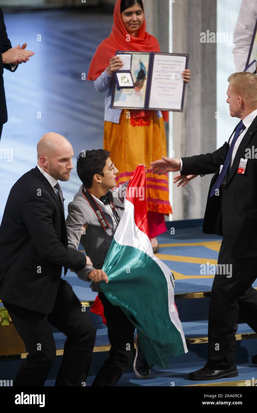 OSLO 20141210. Der Friedensnobelpreis 2014. Ein Mann, der die mexikanische Flagge hält, wird von der Sicherheit weggeführt, nachdem er versucht hat, mit den Friedensnobelpreisträgern Malala Yousafzai aus Pakistan und Kailash Satyarthi aus Indien während der Verleihung des Friedensnobelpreises am Mittwoch, den 10. Dezember 2014 in Oslo, Norwegen, auf die Bühne zu kommen. Den Friedensnobelpreis teilen sich Malala Yousafzai, die 17-jährige Überlebende des Taliban-Angriffs und die jüngste Nobelpreisträgerin aller Zeiten, und der indische Kinderrechtler Kailash Satyarthi am Mittwoch in Oslo. Foto: Heiko Junge/ Stockfoto