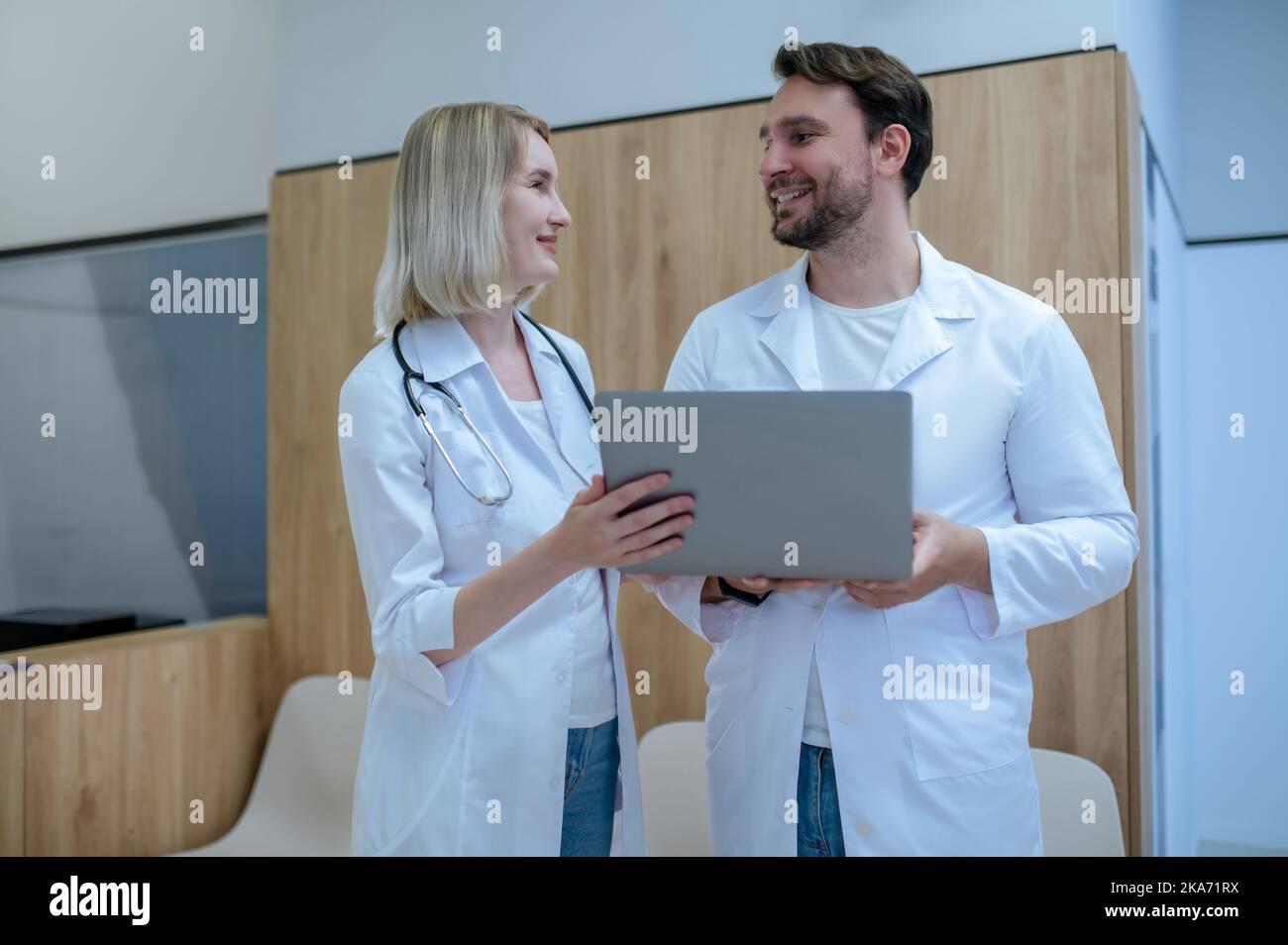 Fröhlicher Arzt und seine Kollegin kommunizieren im Empfangsbereich Stockfoto