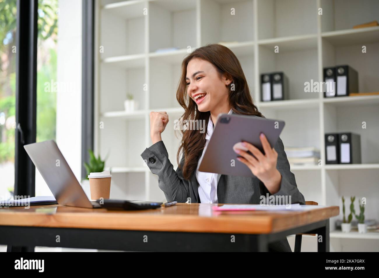 Glückliche und überglückliche junge kaukasische Geschäftsfrau, die auf den Laptop-Bildschirm schaut, glücklich über ihren Projekterfolg oder über den Erhalt einer E-Mail zur Stellenbeförderung. Stockfoto