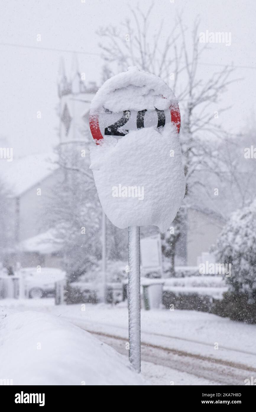 Straßenschild mit 20 km/h, teilweise verdeckt durch Schnee – Schottland, Großbritannien Stockfoto