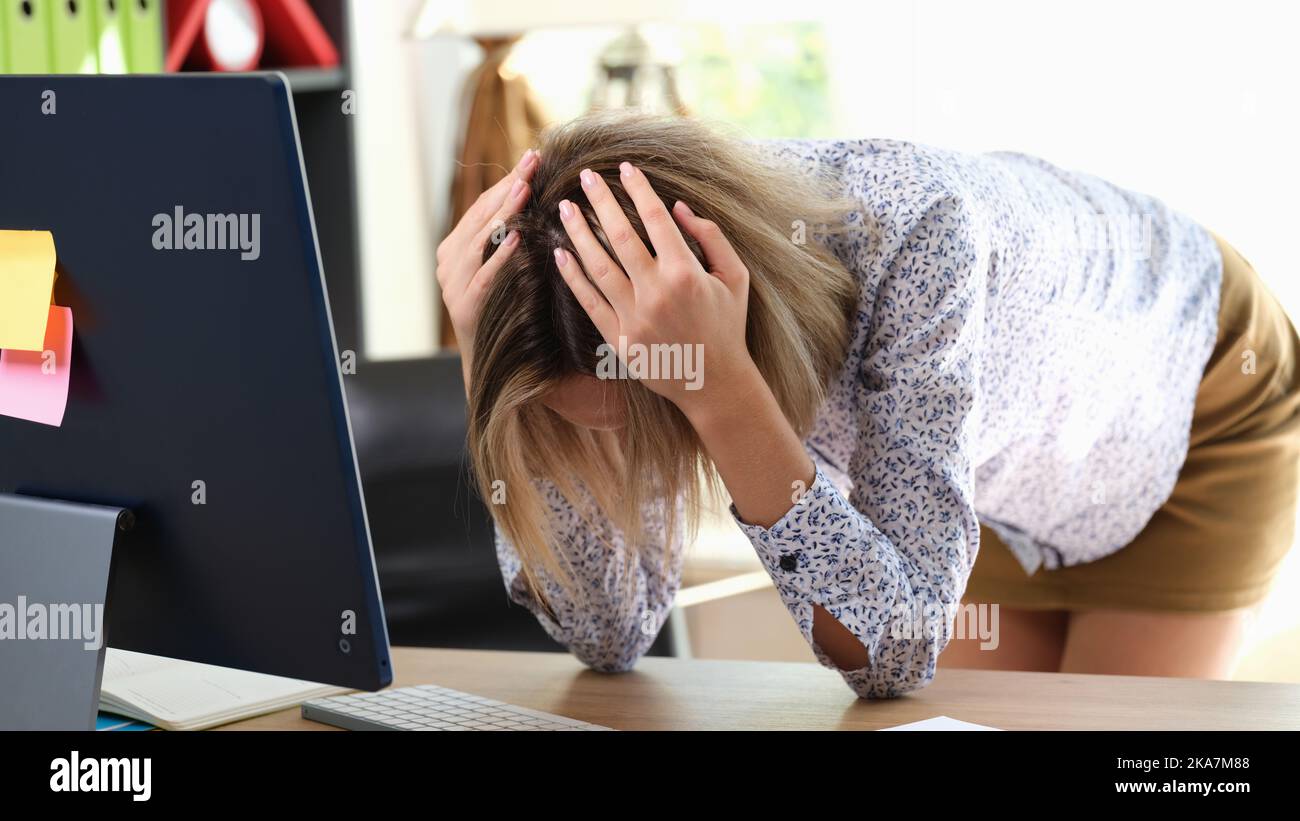 Gestresste Frau, die den Kopf mit den Händen im Büro hält Stockfoto