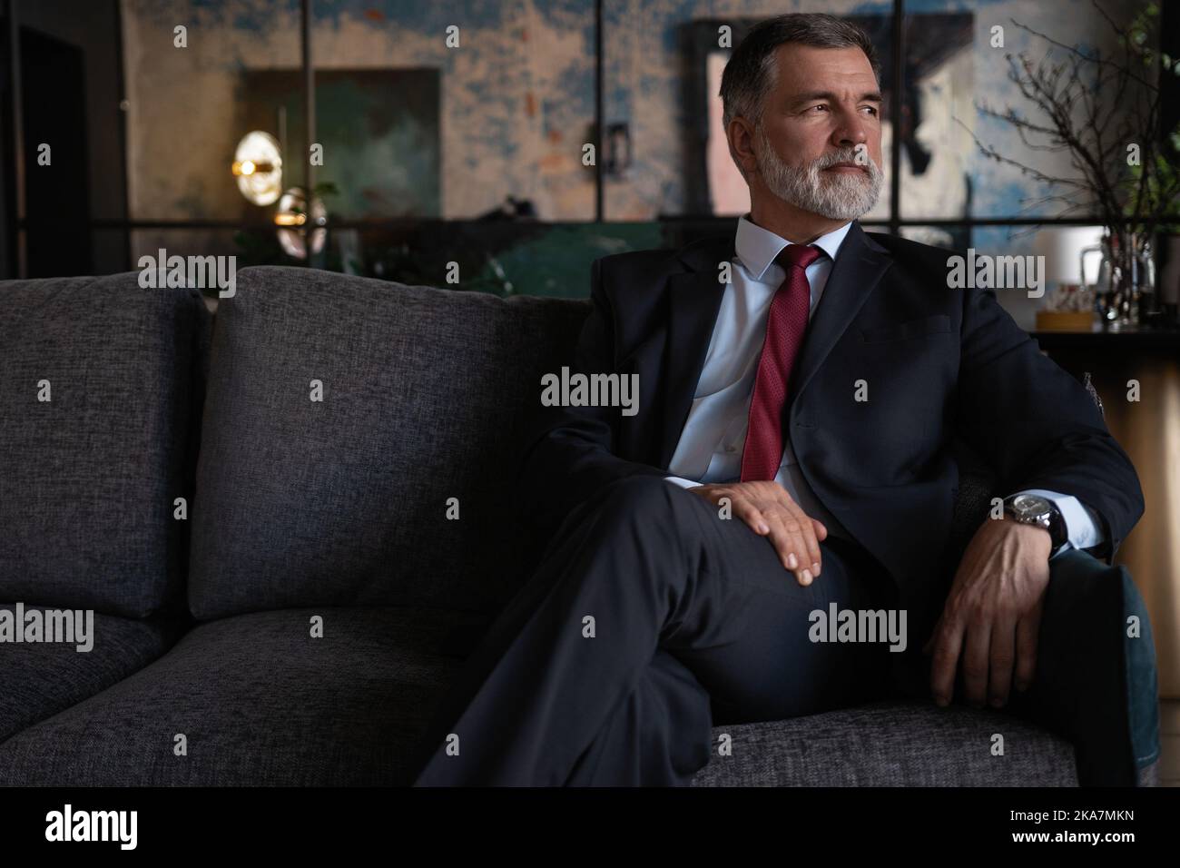 Beginn des neuen Arbeitstages. Reifer Geschäftsmann sitzt auf der Couch im Büro. Stockfoto