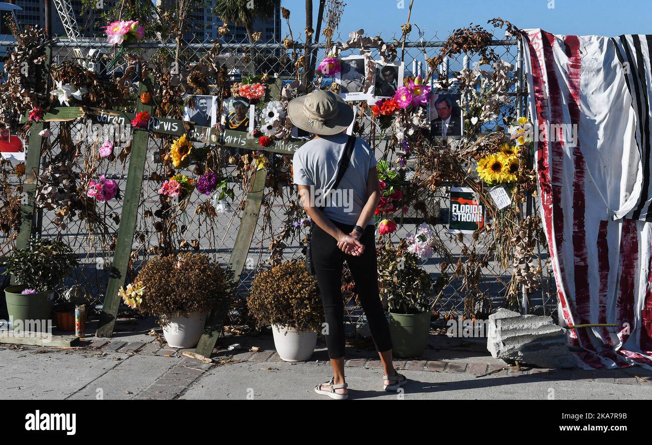 Fort Myers, Usa. 31. Oktober 2022. Eine Frau blickt im Centennial Park in Fort Myers, Florida, auf ein provisorisch anhaltendes Mahnmal mit Blumen, Kreuzen und Fotos für die Opfer des US-Unfallheers Ian. Der Sturm verursachte schätzungsweise $67 Milliarden versicherte Schäden und mindestens 127 stürmbedingte Todesfälle in Florida. Kredit: SOPA Images Limited/Alamy Live Nachrichten Stockfoto