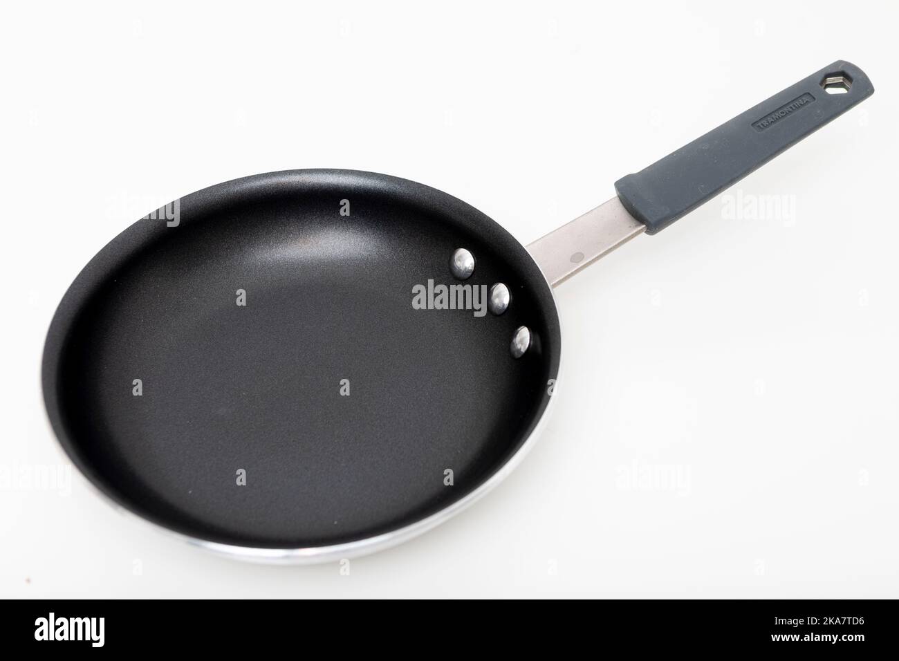Eine antihaftbeschichtete Bratpfanne aus Edelstahl, die auf einen schlichten weißen Hintergrund geschossen wurde. Stockfoto