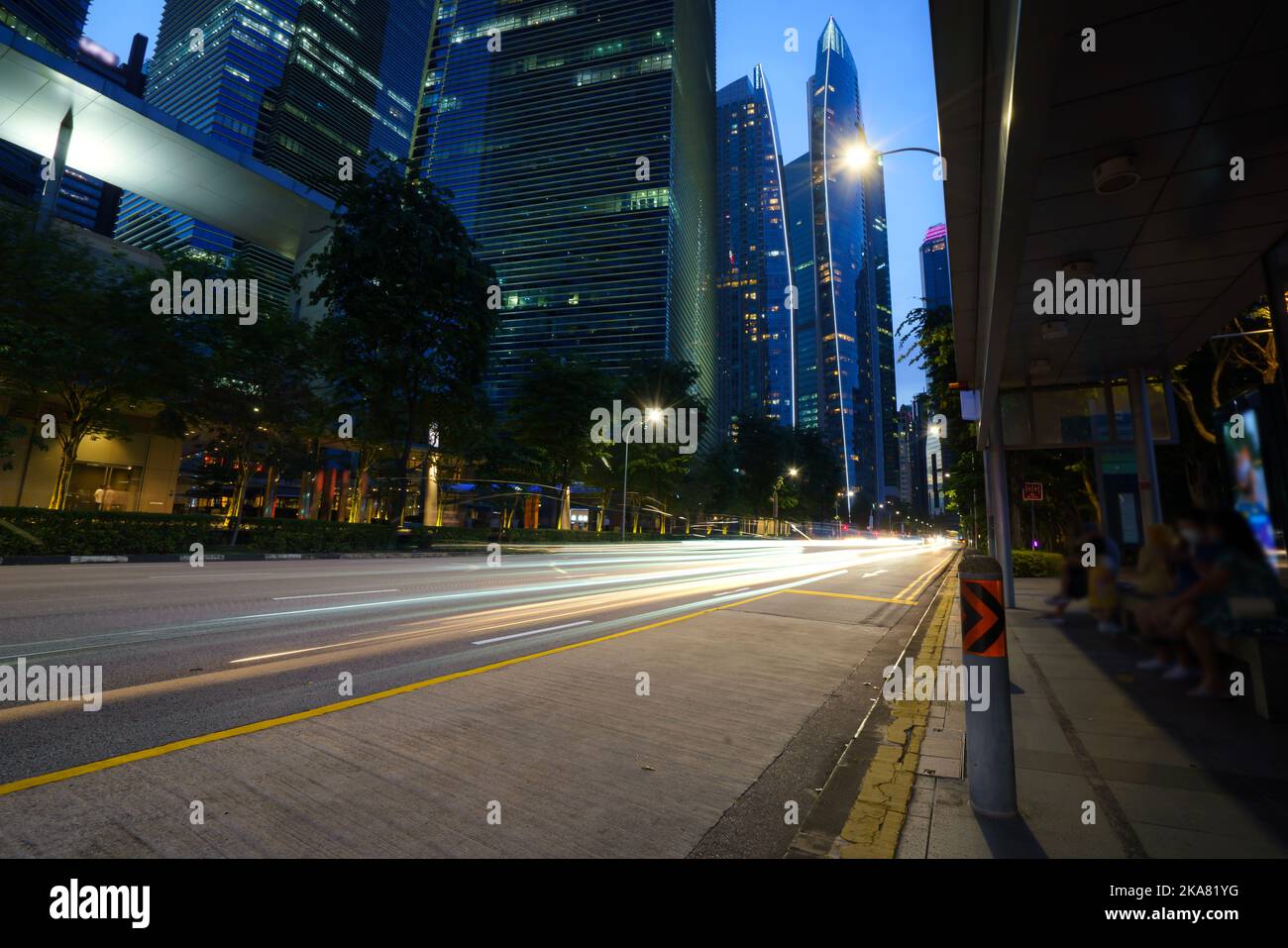Bewegung der Lichter des Autos gegen die Skyline von Singapur bei Sonnenuntergang. Stockfoto