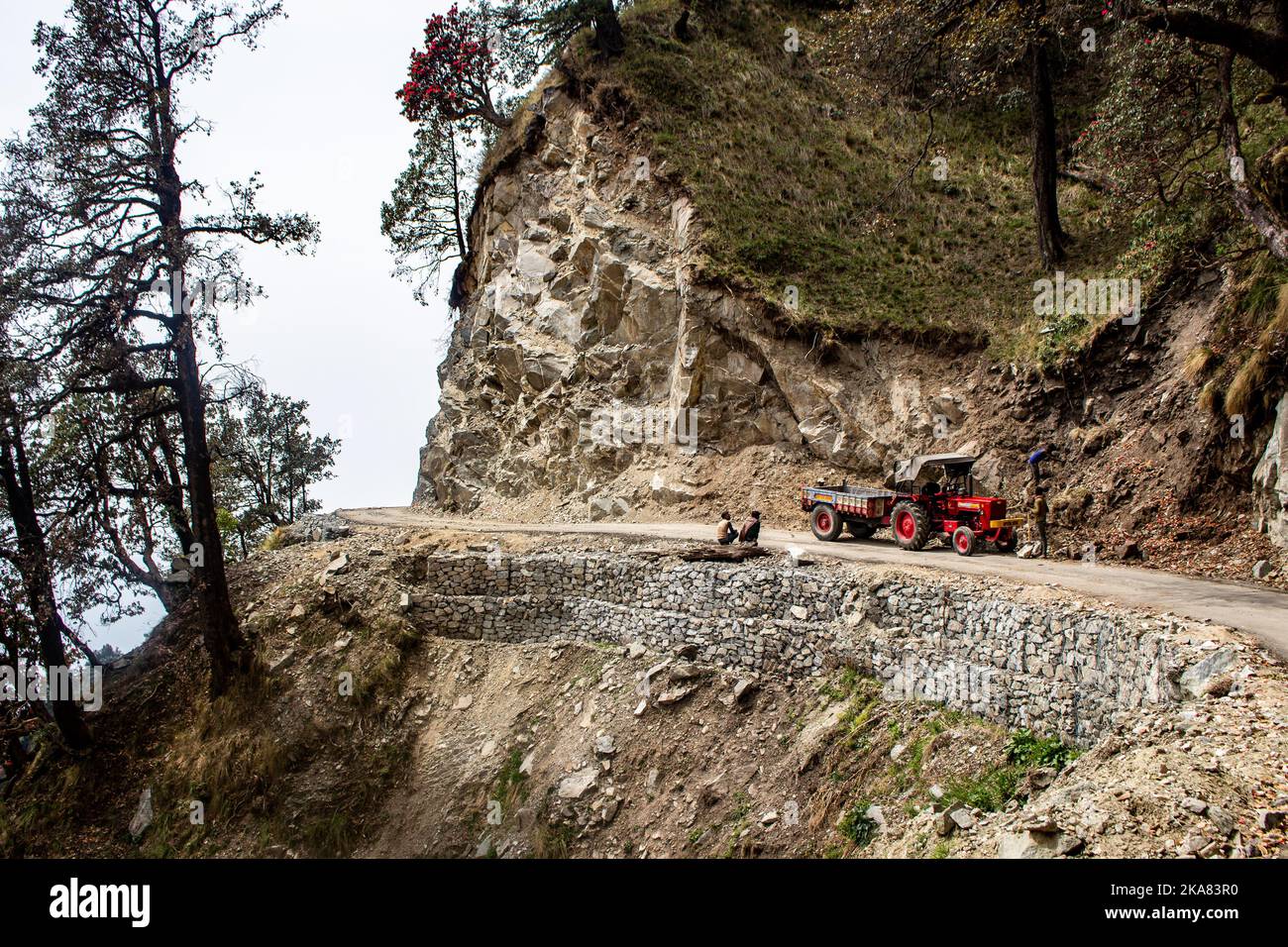 Ein roter Traktor mitten auf der Straße in den Bergen Stockfoto
