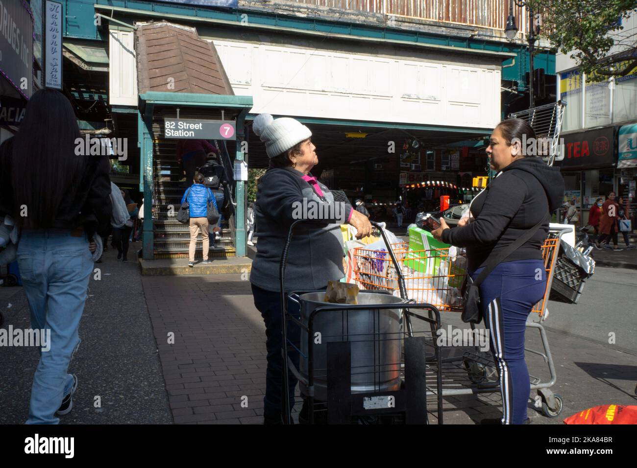 Südamerikanische Verkäufer unterhalten sich auf Spanisch in der 82. Street in der Nähe der erhöhten U-Bahn in Jackson Heights, Queens, New York City. Stockfoto