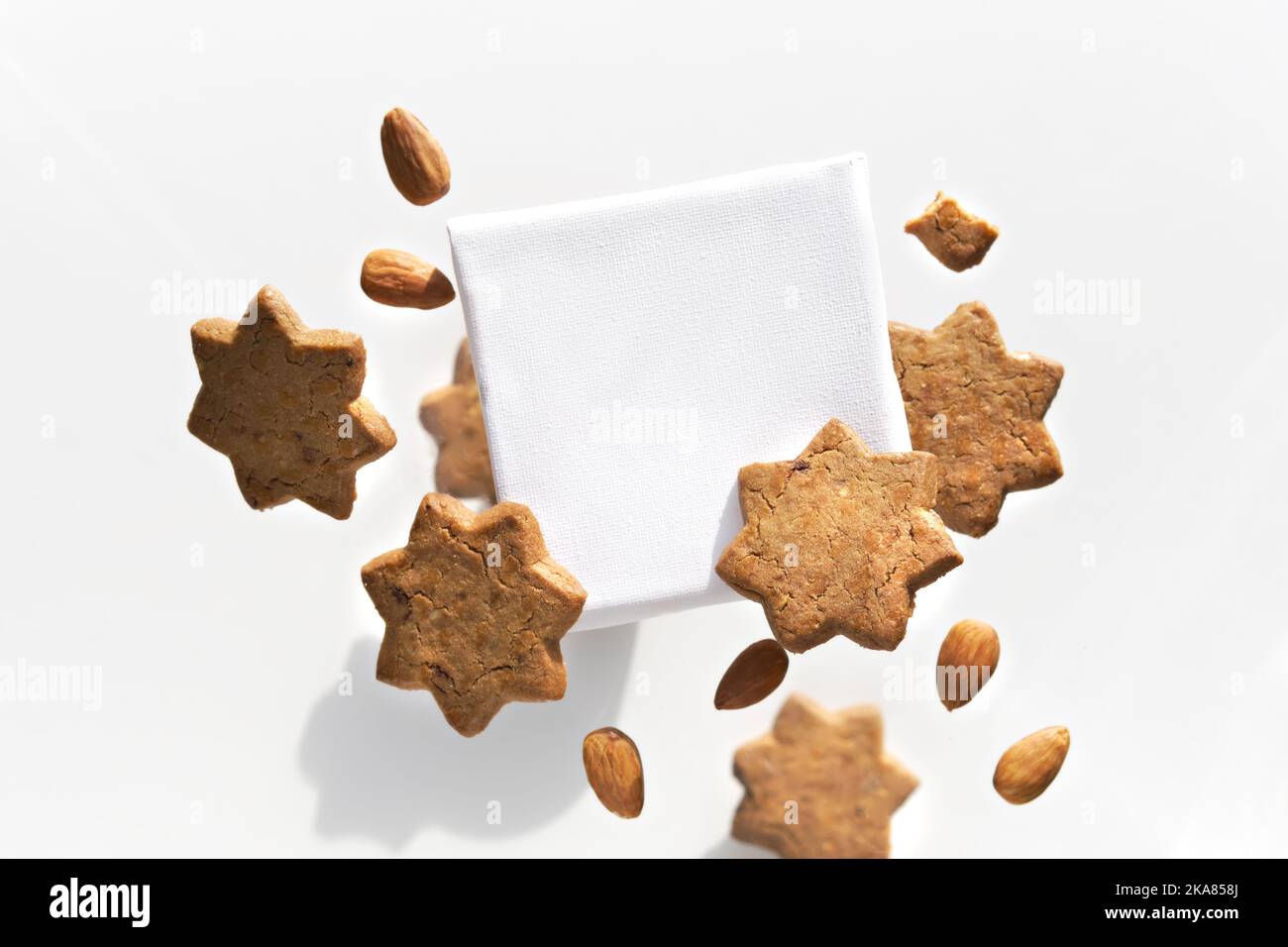 Leinwand mit Text Raum fliegen, schweben mit Stern Cookies Mandeln. Gruppe von leckeren Snacks um Text-Tafel isoliert auf weiß. Kreatives Food Mockup Stockfoto