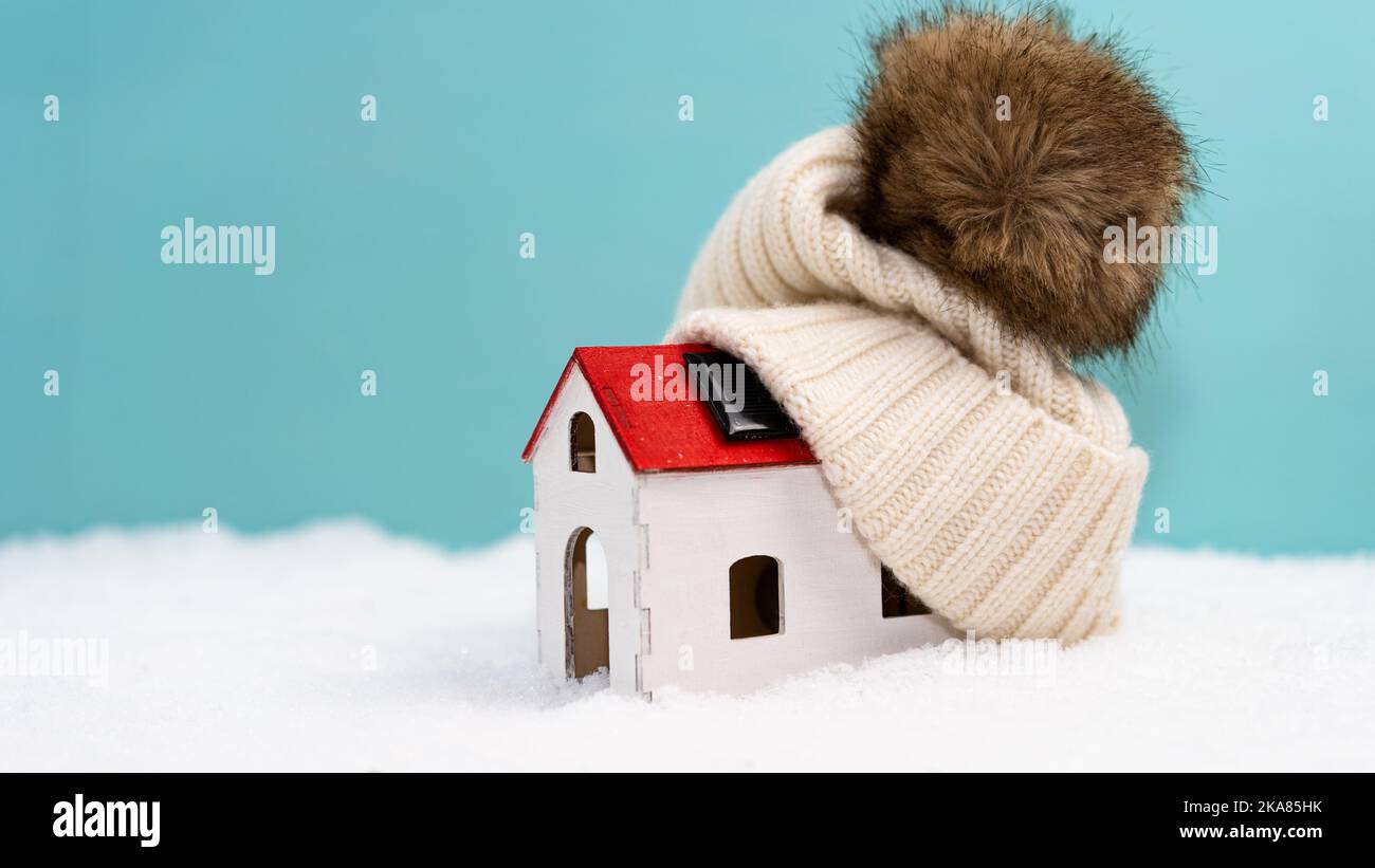 Haus im Schnee. Das Konzept der Zahlung für Heizung, steigende Heizkosten. Beanie auf Modellhaus. Vorbereitung auf den Winter. Stockfoto