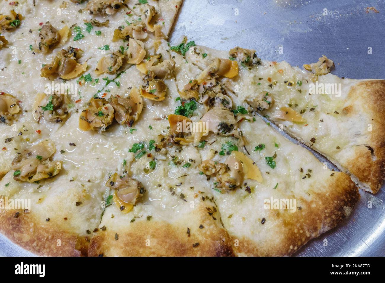 Nahaufnahme von Muschel-Pizza in einem Pizzaladen. Dies ist die lokale Spezialität in Connecticut, USA und wird mit frischen Muscheln und ohne Tomatensauce hergestellt. Es ist oft c Stockfoto