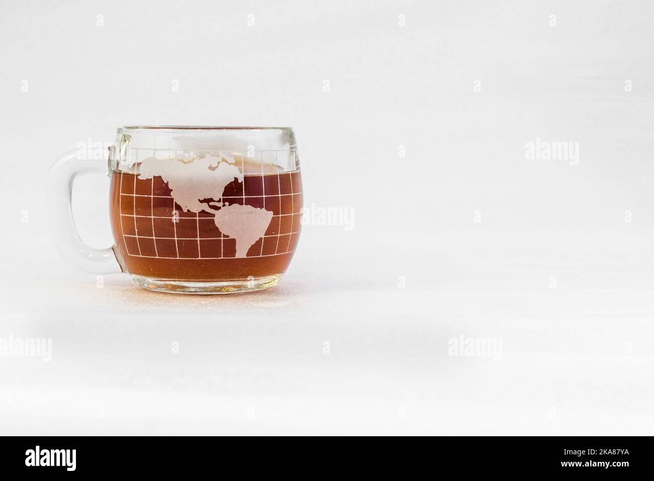 Kaffeebecher aus klarem Glas in Form einer Kugel, gefüllt mit Kaffee auf weißem Hintergrund Stockfoto