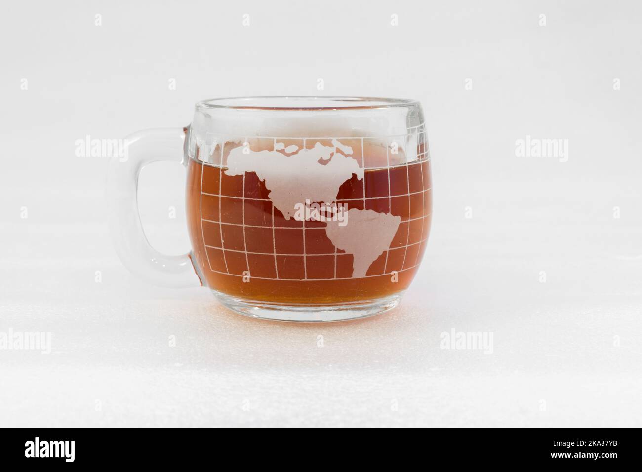 Kaffeebecher aus klarem Glas in Form einer Kugel, gefüllt mit Kaffee auf weißem Hintergrund Stockfoto