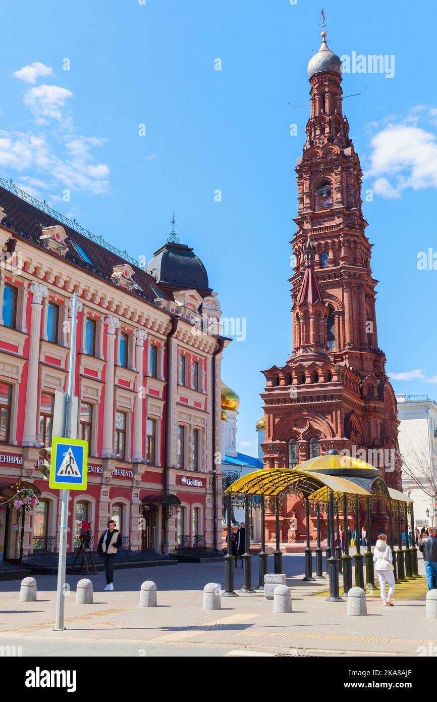 Kazan, Russland - 7. Mai 2022: Blick auf die Straße von Kazan mit dem Glockenturm der Epiphania-Kirche gehen gewöhnliche Menschen die Straße entlang. Vertikales Foto Stockfoto