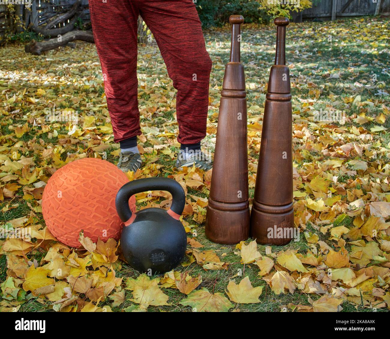 Schwere eiserne Kugelhantel, Slam Ball und hölzerne persische Clubs in einem Hinterhof, Herbstlandschaft Stockfoto