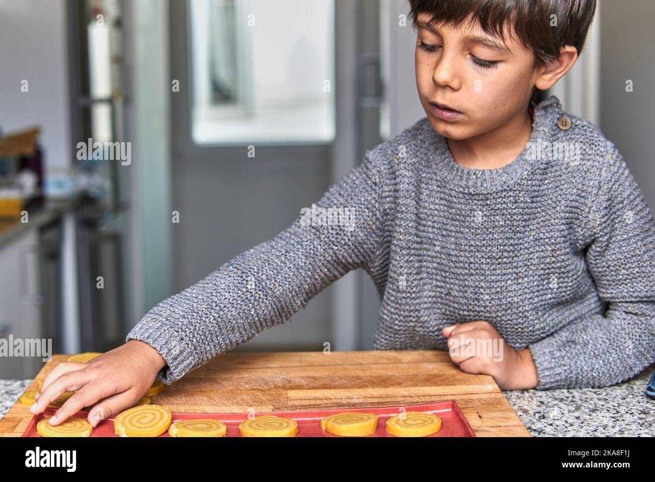 Junge im elementaren Alter, der im Winter Kekse macht Stockfoto