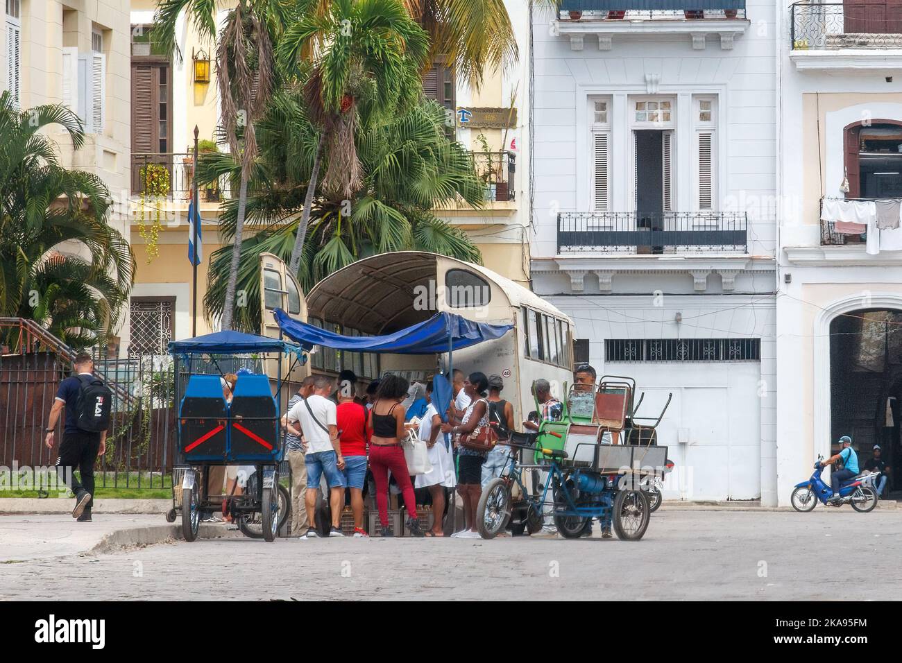 Eine Gruppe Kubaner steht im hinteren Teil eines Lastwagens an, der Lebensmittel auf einer Straße in der Stadt verkauft. Stockfoto