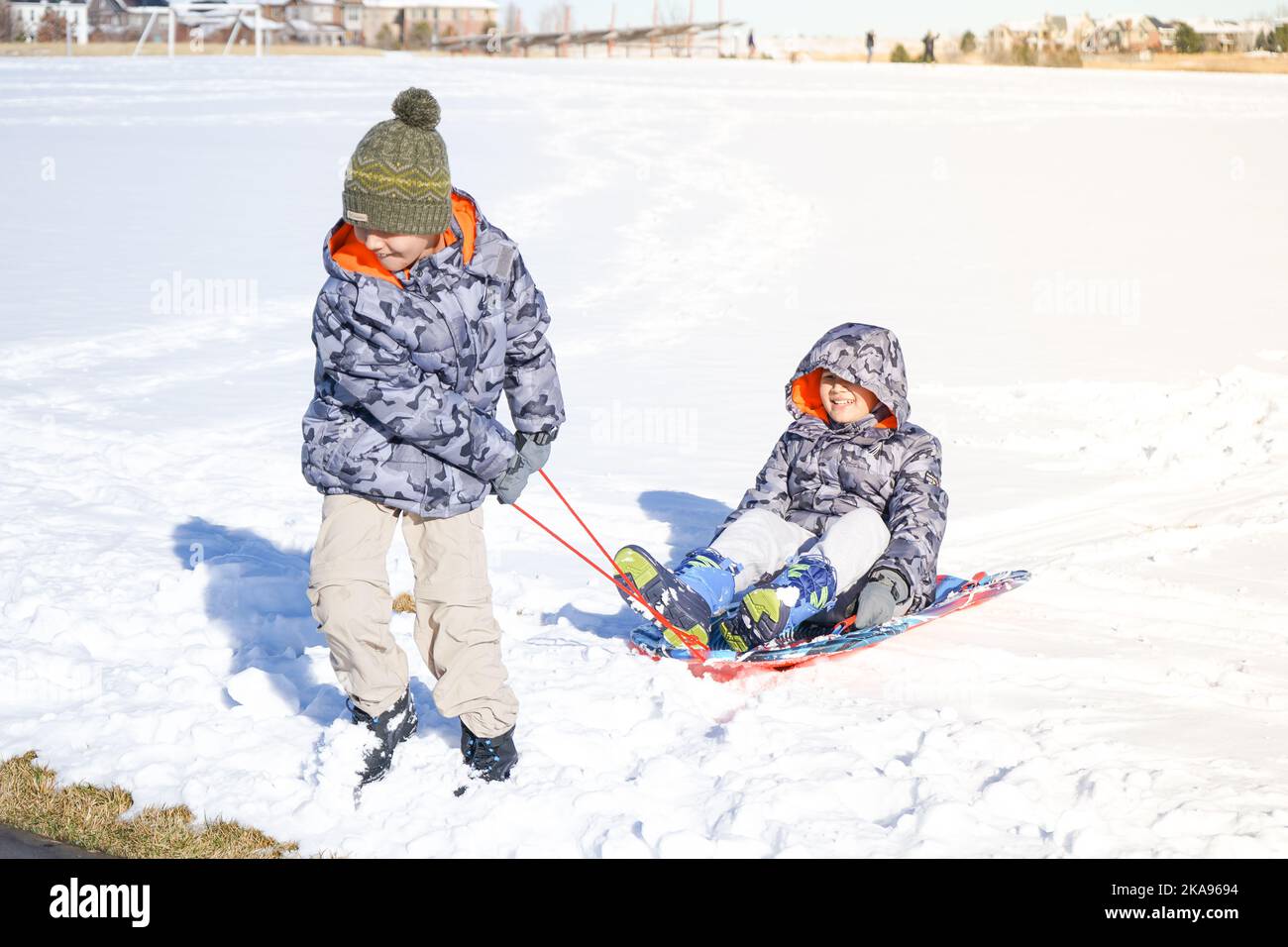Kinder lachen haben Spaß Rodeln an einem sonnigen Tag im Winter denver Stockfoto