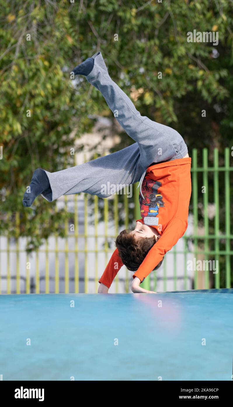 Kind macht Salto im Freien in aufblasbaren Luftkissen springen Türsteher Spielplatz Stockfoto