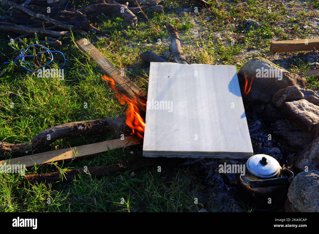 Marmor am Lagerfeuer zum Kochen und Teekannen am Feuer im Freien an einem sonnigen Sommertag Stockfoto