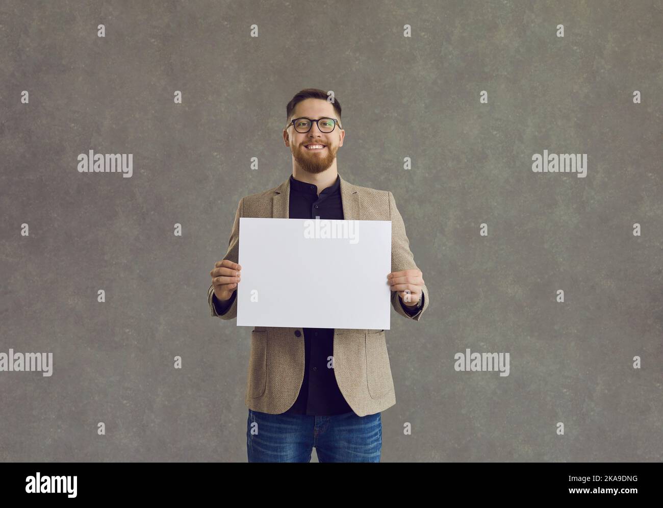 Lächelnder Geschäftsmann mit leerem Papierposter und Blick auf die Kamera Stockfoto