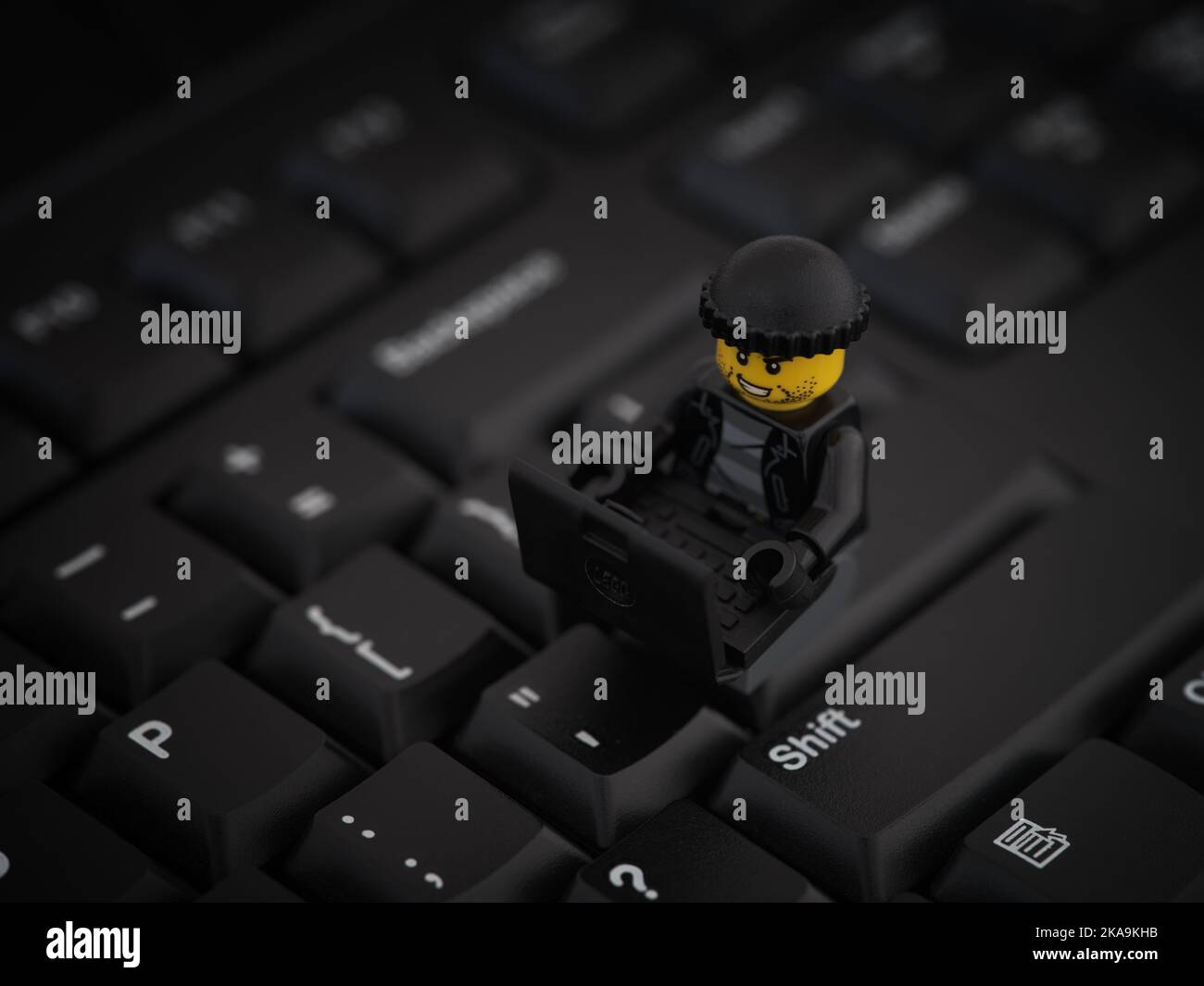 Tambov, Russische Föderation - 25. August 2022 Eine Minifigur eines Lego-Räubers, die auf einer Computertastatur sitzt und ein Netzwerk mit einem Laptop hackt. Stockfoto