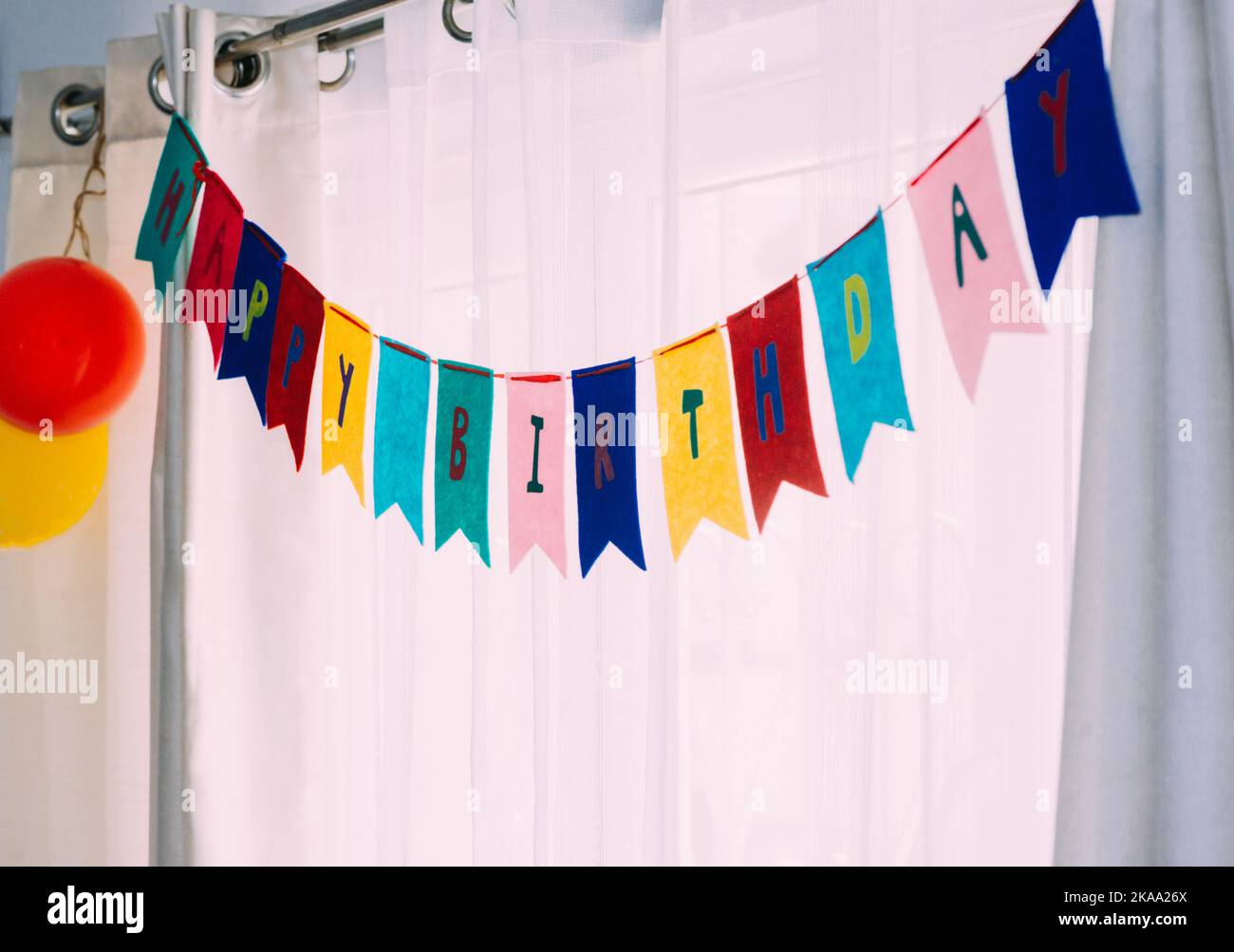 Happy Birthday Banner Party Hintergrund vor weißen Vorhängen und Tageslicht Stockfoto