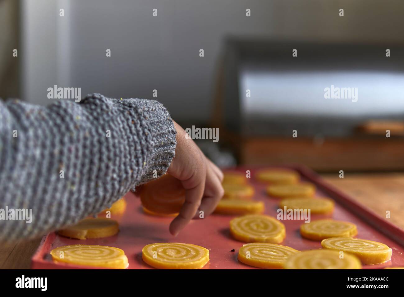 Junge im Elementaralter, der Cookies auf ein Silikontablett legte Stockfoto