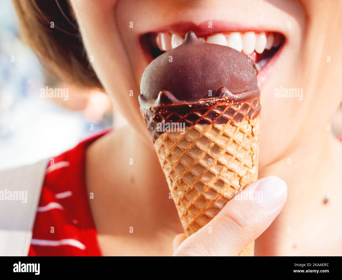 Frau im roten Hemd isst Eis. Nahaufnahme des kalten Nachtisch. Sommerspaß. Stockfoto