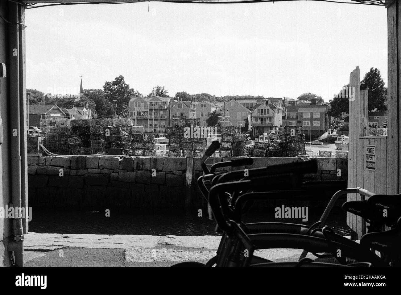 Sever Leihräder in Silhouette mit einem Pier und Hummerfallen im Hintergrund in Rockport, Massachusetts. Das Bild wurde auf analogem Schwarz-ein-Bild aufgenommen Stockfoto