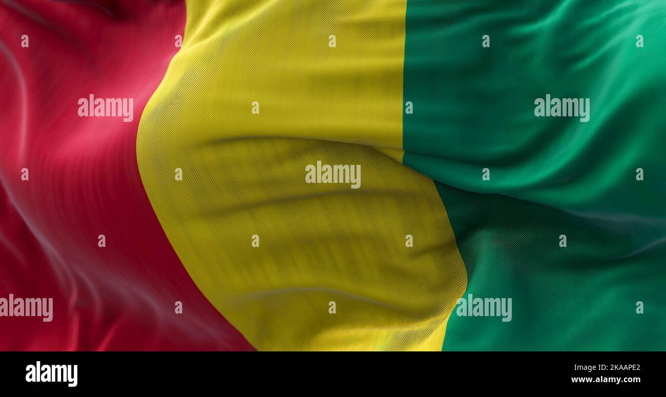 Nahaufnahme des Winkens der Nationalflagge von Guinea. Die Republik Guinea ist ein westafrikanischer Staat. Texturierter Hintergrund aus Stoff. Selektiver Fokus. Nahtlose Schleife i Stockfoto