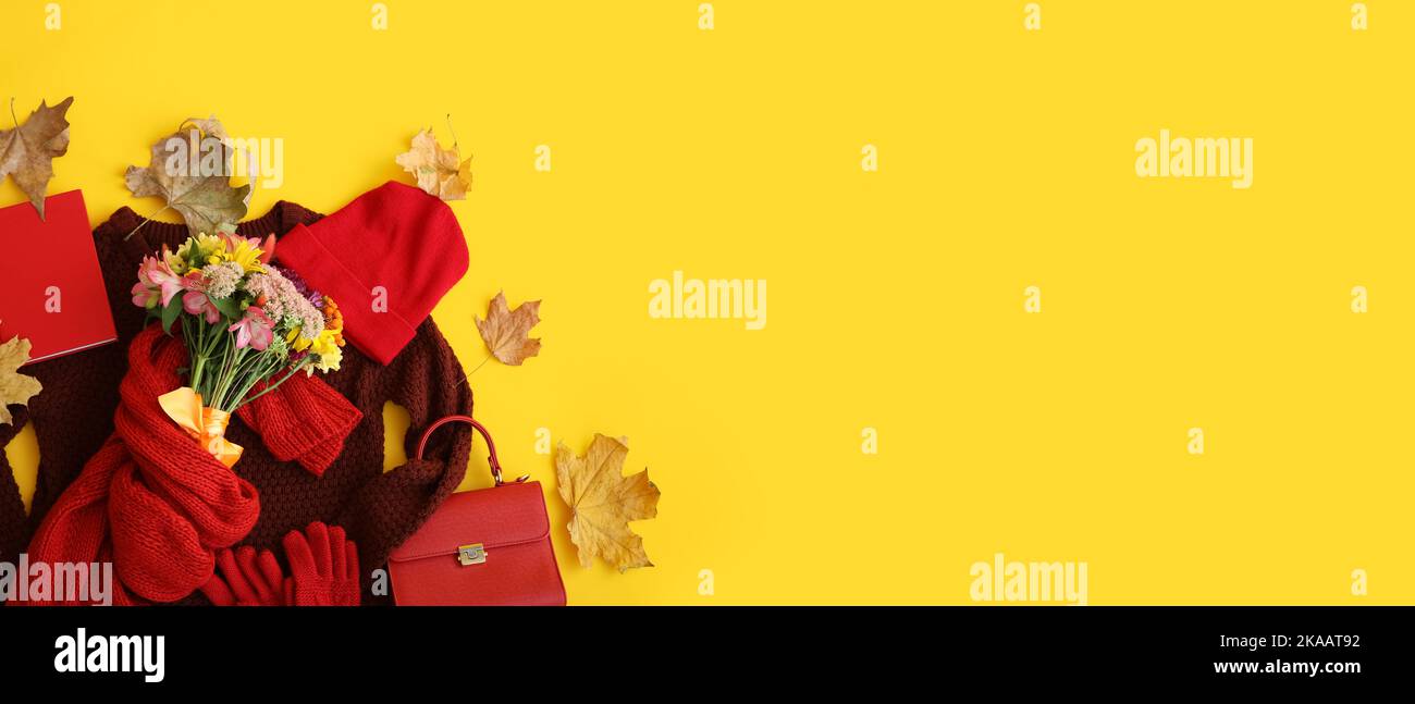 Stilvolle weibliche Kleidung und Accessoires mit Blumenstrauß und Herbstblättern auf gelbem Hintergrund mit Platz für Text Stockfoto