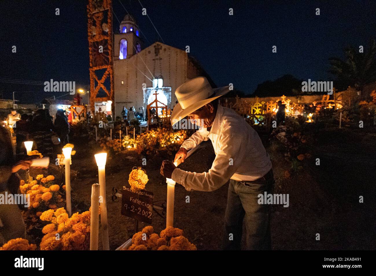 Morelia, Mexiko, 1. November 2022, zündet ein indigener Mann während der Totenfeier auf dem Friedhof von Arocutin, Michoacan, Mexiko, eine Kerze an. Die indigenen Purepecha dieses Dorfes bereiten dieses jährliche Ritual des Gedenkens vor, indem sie Altäre mit Ringelblumen, Kerzen und dem Lieblingsessen oder Getränk der Verstorbenen bauen. Die Mahnwache findet in der Nacht des 1.. November statt und hat sich zu einer wichtigen Touristenattraktion im zentralmexikanischen Bundesstaat Michoacan entwickelt. Brian Overcast/Alamy Live News Stockfoto