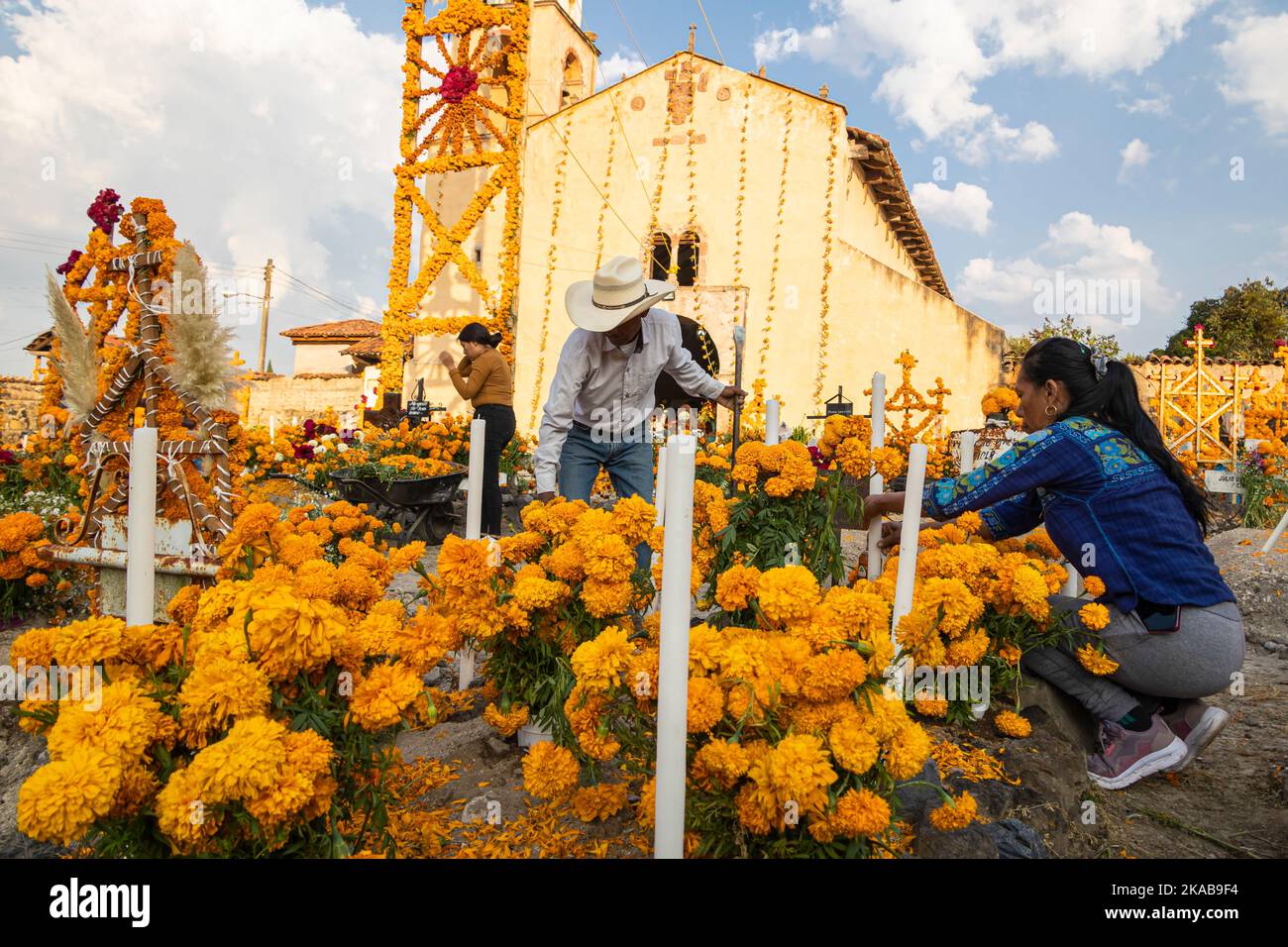 Morelia, Mexiko, 1. November 2022, Ein Paar setzt während der Feier des Totenfestes auf dem Friedhof von Arocutin, Michoacan, Mexiko, einen letzten Schliff an einem Altar. Die indigenen Purepecha dieses Dorfes bereiten dieses jährliche Ritual des Gedenkens vor, indem sie Altäre mit Ringelblumen, Kerzen und dem Lieblingsessen oder Getränk der Verstorbenen bauen. Die Mahnwache findet in der Nacht des 1.. November statt und hat sich zu einer wichtigen Touristenattraktion im zentralmexikanischen Bundesstaat Michoacan entwickelt. Brian Overcast/Alamy Live News Stockfoto